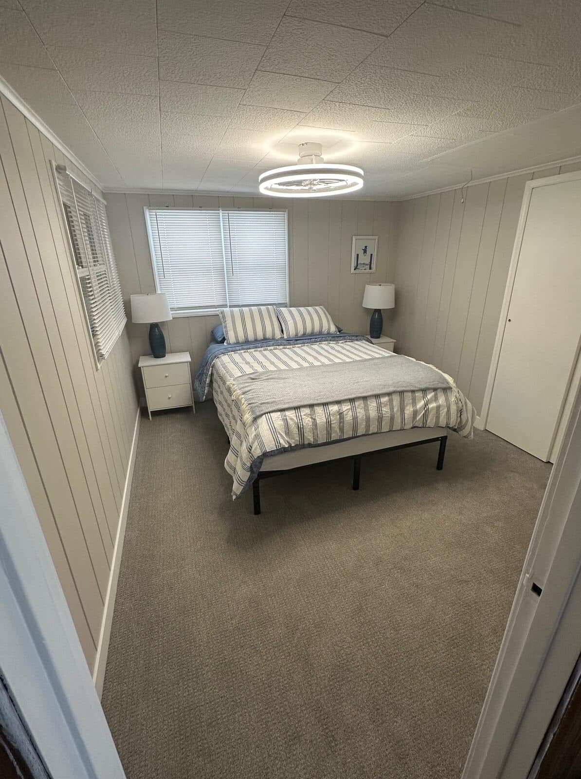 Lake cottage bedroom with circular LED fixture and grey carpet